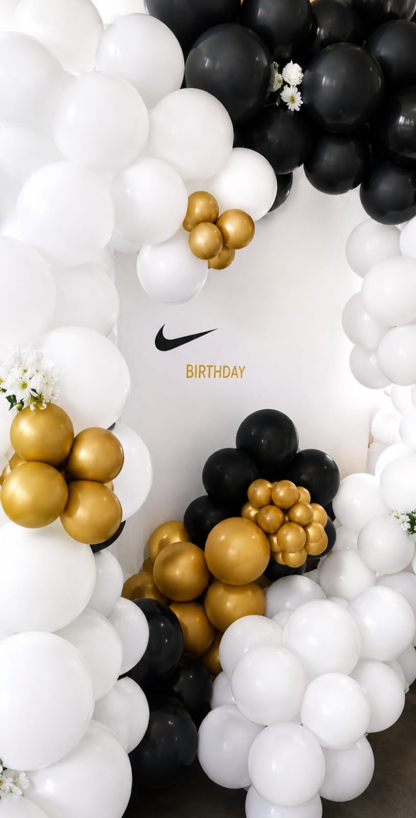 Black, white and gold balloon arch backdrop styled for a birthday