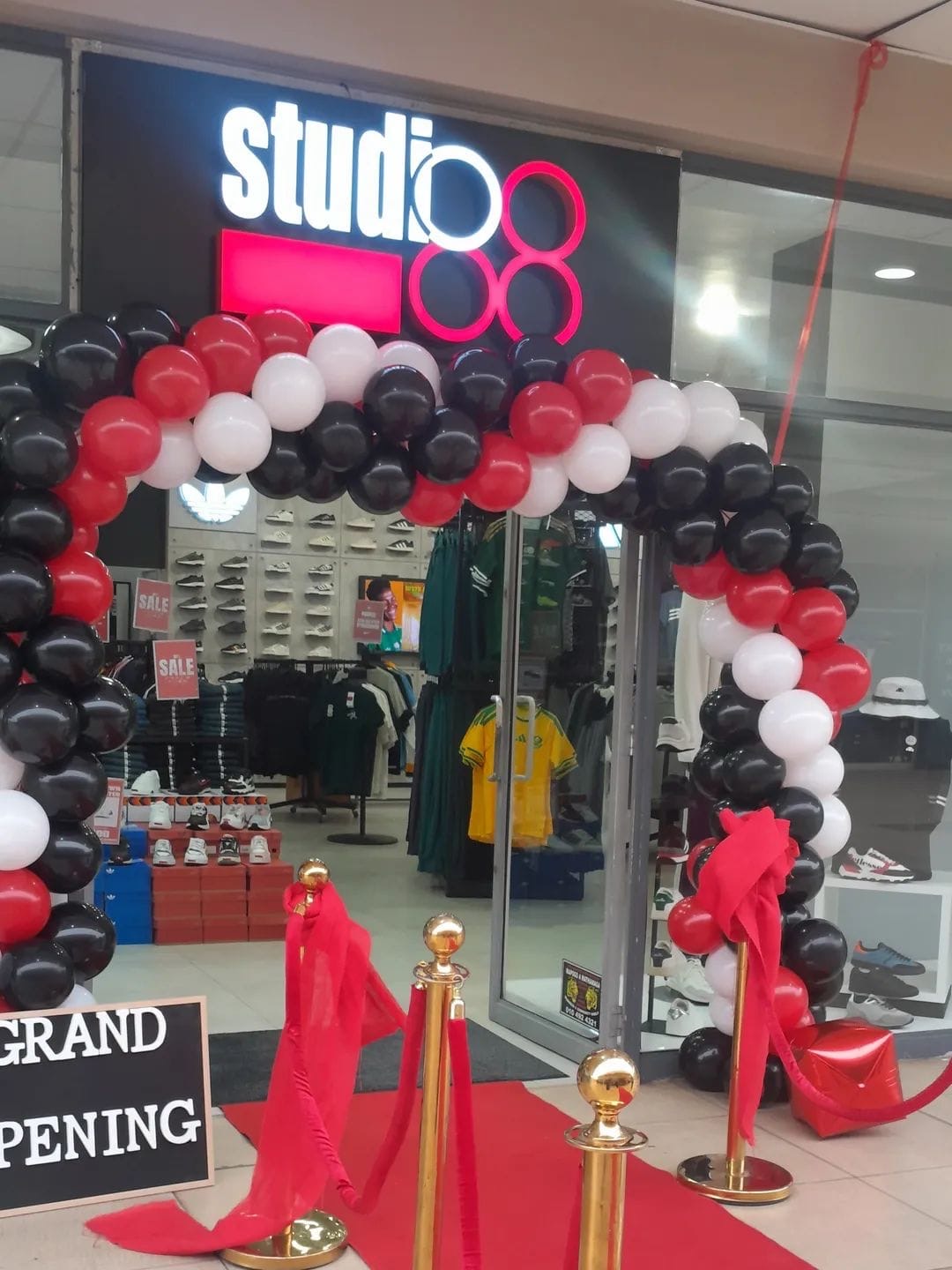 Red, black and white balloon arch with red carpet at a Studio 88 grand opening